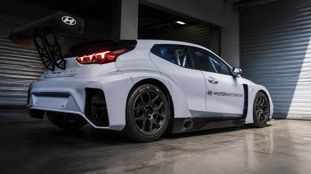 Weißer Hyundai Motorsport Rennwagen mit großem Heckflügel in dunkler Garage.