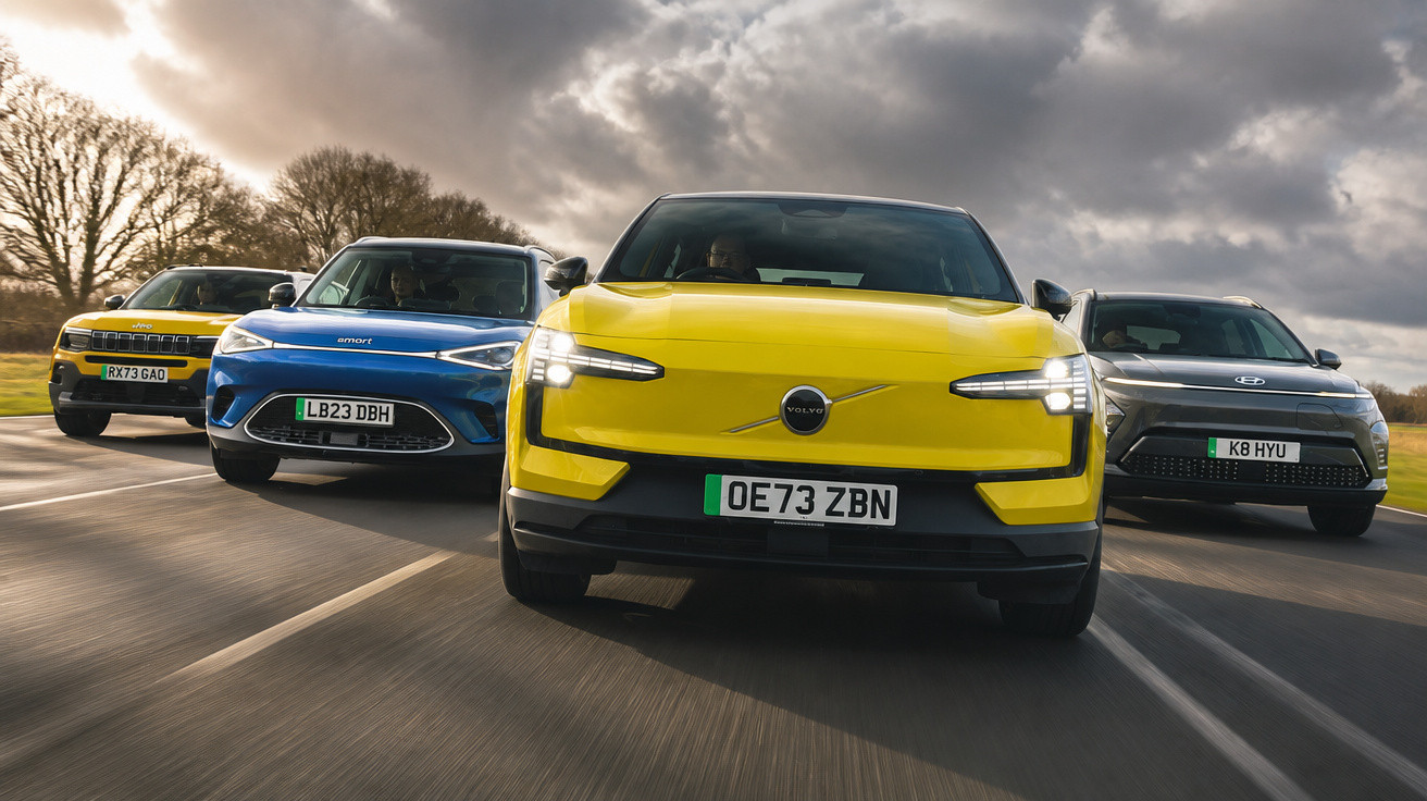 Vier verschiedene moderne Elektro-SUVs fahren nebeneinander auf einer Landstraße bei bewölktem Himmel.
