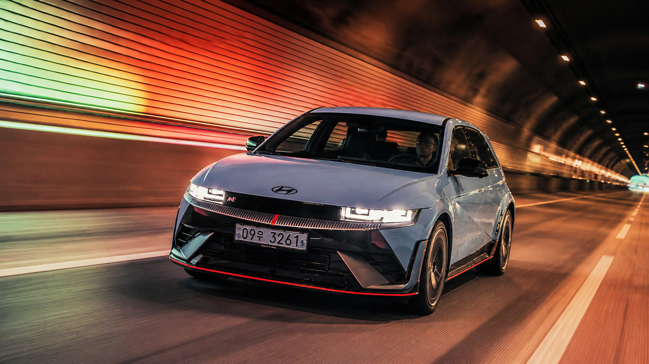 Hyundai sportliches Auto fährt mit eingeschaltetem Licht durch einen beleuchteten Straßentunnel.