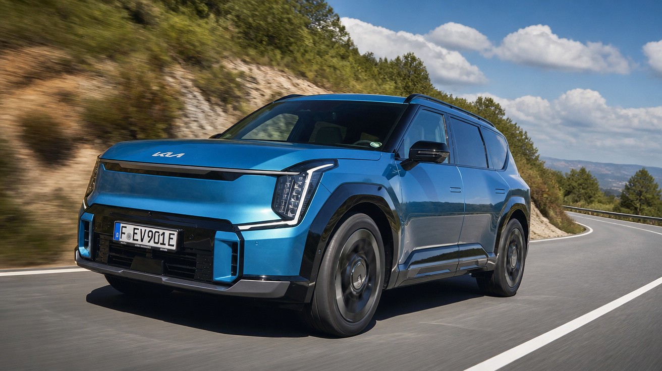 Blauer moderner Kia SUV fährt auf kurviger Straße bei sonnigem Wetter im Grünen.